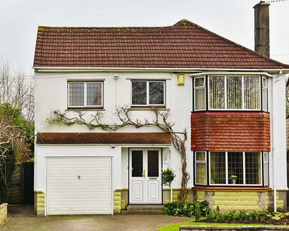 Detached 1930s house with white render, red tiled roof and bay window, unoccupied during probate