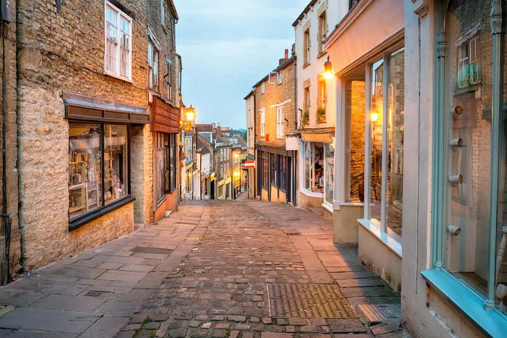 A UK high street at dusk with empty shopfronts and residential flats above, showing the type of mixed-use property requiring specialist unoccupied cover.