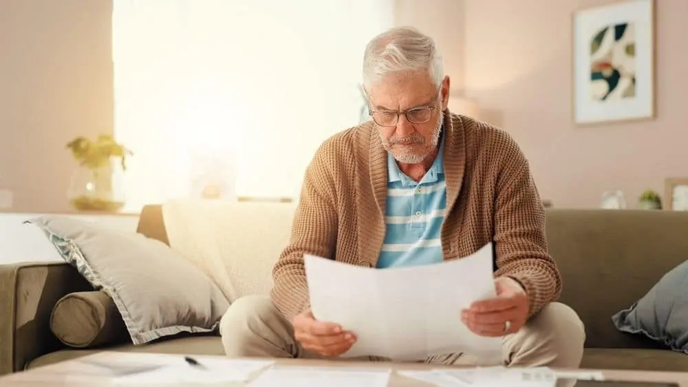 Man at home searching through a deceased person's documents for a Will before arranging Missing Will Insurance