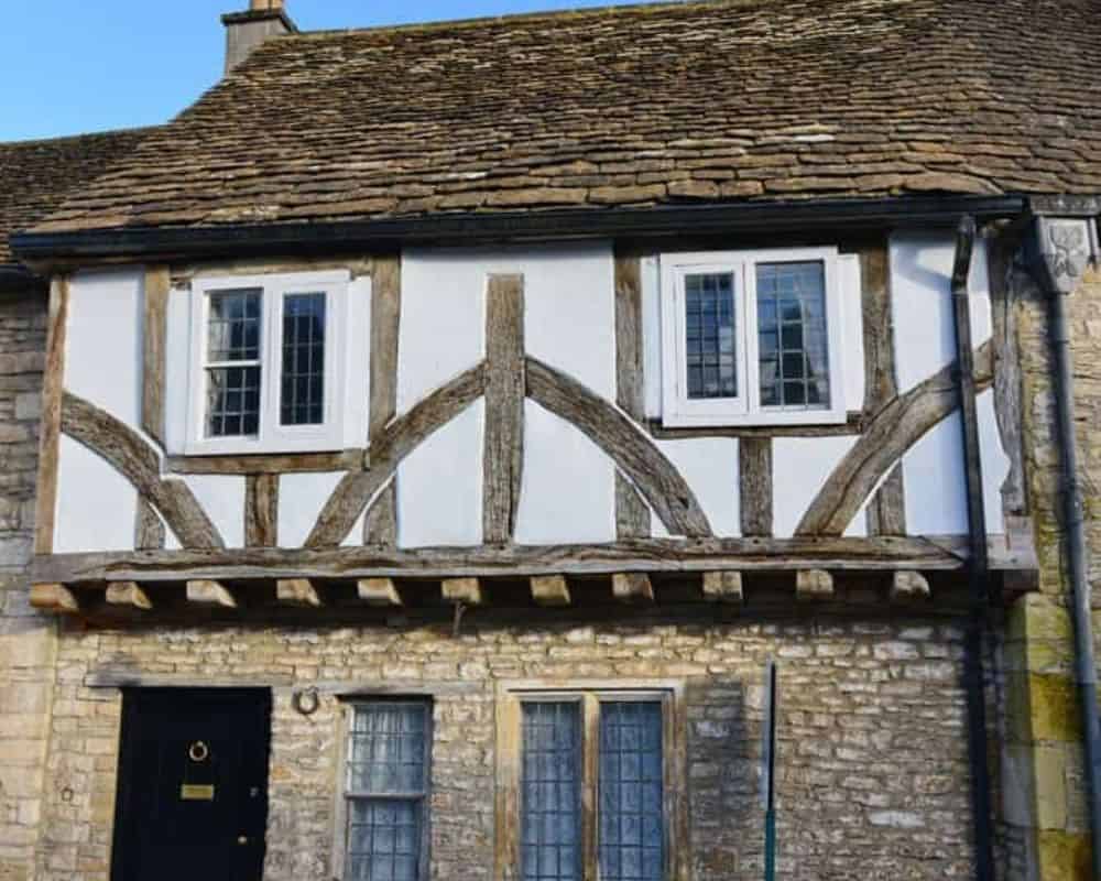 Period timber-framed house with stone walls and a stone-slate roof.
